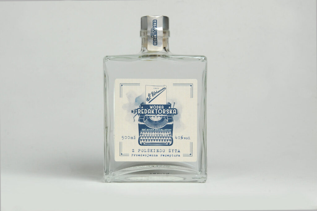 Kwadratowa duża butelka z wódką żytnią Redaktorską z ładną etykietą. Butelka stoi na białym tle.
