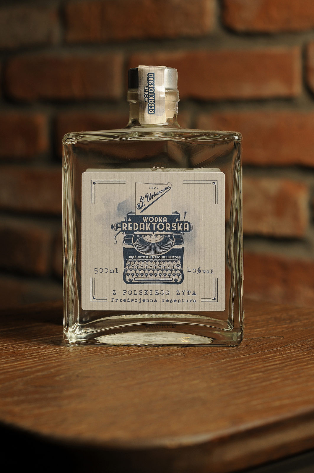 Duża kwadratowa butelka wódki żytniej Redaktorskiej. Stoi na stole. Ładna reto etykieta.